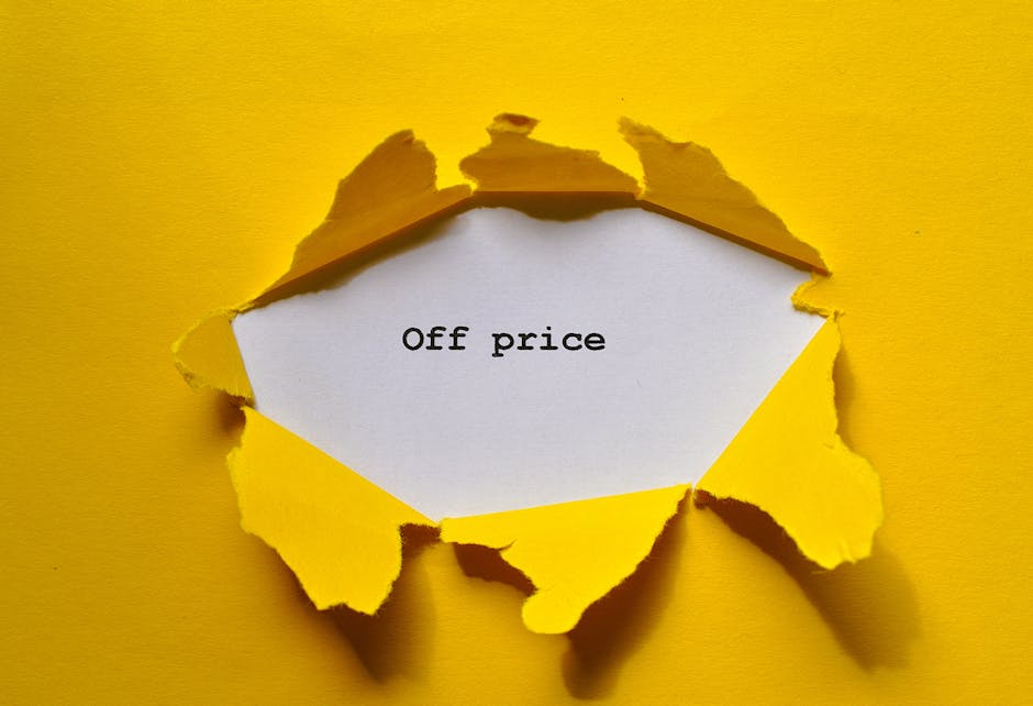 A yellow paper background with a large, irregularly torn hole in the center reveals a white card inside, printed with the words 'Off price' in black text. The torn edges of the paper are rugged and uneven, creating shadows that add depth to the image. The white card is partially visible through the tear, suggesting a message about discounts or reduced pricing. The overall scene is well-lit, highlighting the contrast between the yellow background and the white card, which may relate to promotional aspects in a house removals or packing context, such as discounted services offered by Man with Van Preston during a home relocation or furniture transport process.